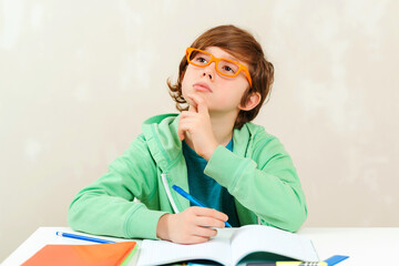Fototapeta na wymiar Boy thinking and doing homework. Little student boy studying and reading books.