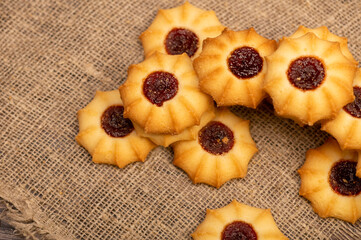 Homemade pastry cookies with jam on a background of homespun fabric with a rough texture, close-up, selective focus.