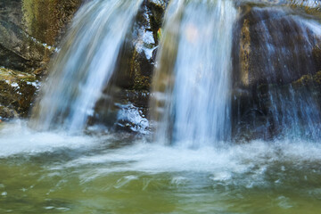 waterfall jets in a mountain stream between rocks, the water is blurred in motion