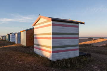 The setting sun hitting the back of some English beach huts on a beach in Kent.	