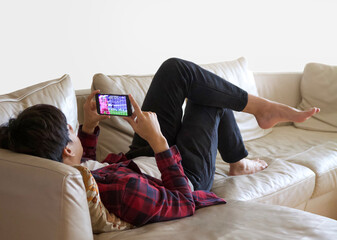 He is watching a soccer game with his smartphone at home.