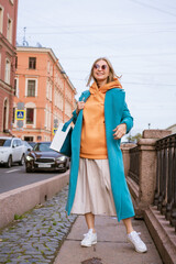 Fototapeta na wymiar Happy woman posing on city streets in blue coat