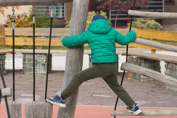 A nimble boy climbs a rope ladder in a hanging city on a playground