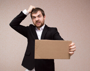 Businessman in suit holding a cardboard with copy space/ unemployment and crisis concept.