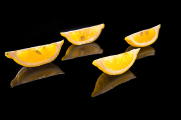 Lemon slices on a black background with reflection