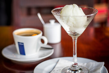 a scoop of vanilla ice cream in a martini glass with a cup of espresso on the side