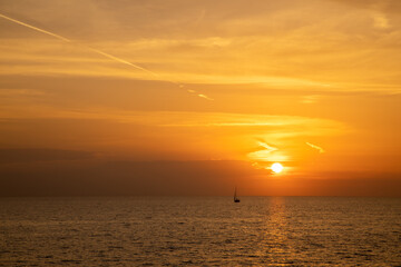 Naklejka na ściany i meble Segelboot auf dem Ozean vor der untergehenden Sonne