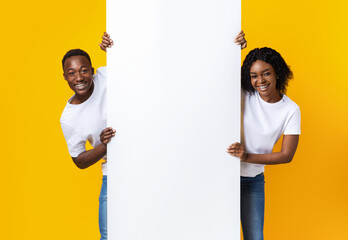 Cheerful african couple holding empty board for advertisement