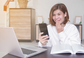 young asian business woman work from home and video conference via application on mobile phone,she 's smiling and touch her mouth for send a kiss to her colleagues