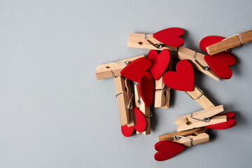 Clothespins with wooden hearts at the end on a gray background Valentine's day holidays decoration