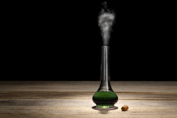 Glass bottle with magic green potion on a dark background. Magic elixir or poison. Potion with smoke and skull.