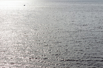 Water ripples on a surface lake in the distance a small boat with fishingman