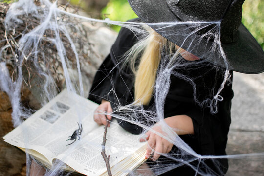 Halloween and kids. Girl in a black hat with spiders and cobwebs, portrait