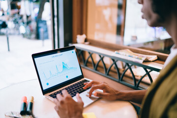 Unrecognizable ethnic man using laptop in cafe
