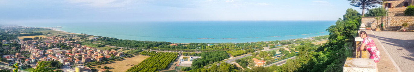 Fototapeta na wymiar Ultra wide aerial view of the Marche sea coast with a woman admiring the view
