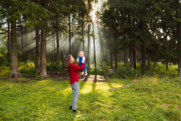 Mother walk with baby in summer forest, beautiful light