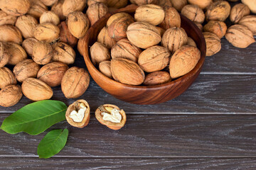 walnuts in a wooden bowl on a wooden background. walnuts in a bowl and a bunch of walnuts close-up.