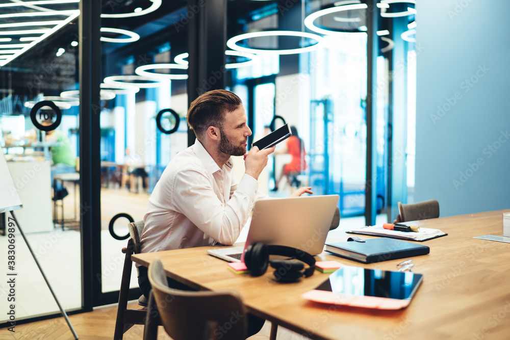 Poster caucasian businessman recording audio message for sending voice sms during smartphone chatting with 