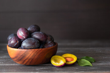 Fototapeta premium ripe blue plums in a bowl on the table close-up. background with ripe blue plums and plum halves close-up. copy of space and plum.