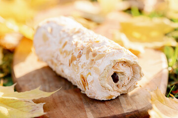 dessert meringue roll with white pistachio topping on autumn background