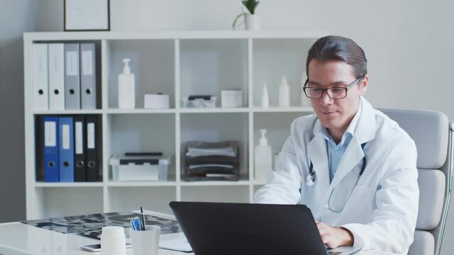 Professional medical doctor working in hospital office using computer technology.