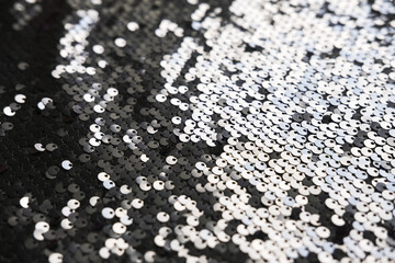 Sequin fabric texture. Shiny silver sparkling background. Clothing piece of glitter metallic for a glamorous party, celebration. Close-up.