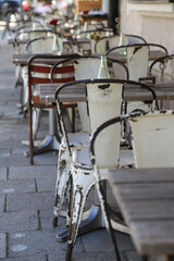 Charmantes vintage outdoor Restaurant mit verwitterten weißen Stühlen und Holztischen dekoriert mit Gläsern, Blumenvasen, Bestecken und Servietten