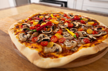 Top view of the finished pizza just taken out of the oven. Next is a plate with herbs. Vegan food.