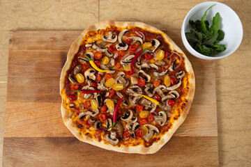 Top view of the finished pizza just taken out of the oven. Next is a plate with herbs. Vegan food.