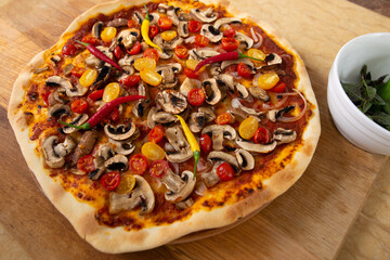 Top view of the finished pizza just taken out of the oven. Next is a plate with herbs. Vegan food.