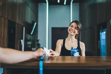 Cropped image of positive caucasian female taking card for access to gym and locker room with copy...