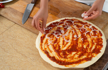 A view of the chef's hands laying out the onion on top of the piece. Making vegan pizza without cheese.