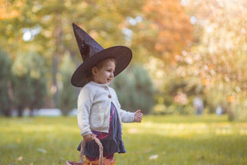happy haloween. portrait of  cute toddler girl in witch hat in the autumn  forest.