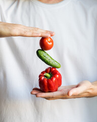 Vegetables pepper, cucumber and tomato between male hands on white background. Selective focus. Dieting, healthy eating, vegan concept