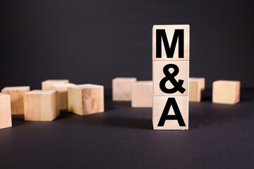 M&A or Merger and Acquisition. text on wood cubes. on black background