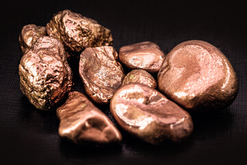 native copper nuggets isolated on black background, ore for industrial use in electrical wires and...