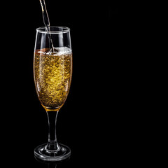 Champagne with bubbles in a glass on a black background. Place for text