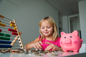 child counting money, girl put coins into piggy bank