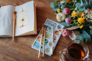 Artist's desktop with watercolors, palette, sketchbook