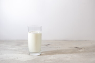 Milk is poured into a glass. On a light background