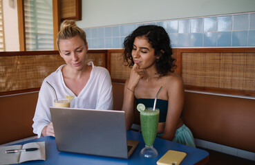 Diverse female copywriters watching webinar video on content website during collaborative...