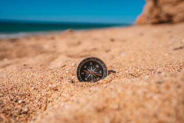Background image of compass lying in the sand on the beach with sea view, travel concept