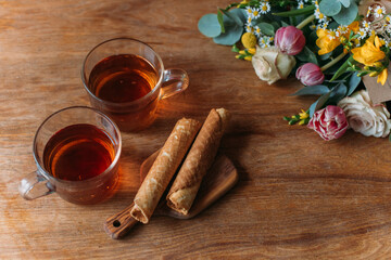 Still life. Table with mugs of tea, cookies and flowers