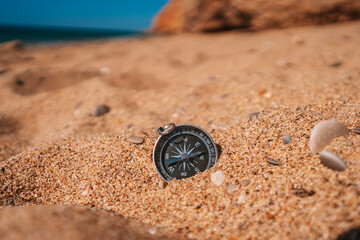 Background image of compass lying in the sand on the beach with sea view, travel concept