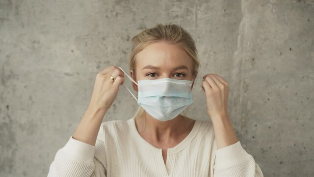 Sweden scandinavian COVID-19 doctor woman taking off face mask for coronavirus protection throw drop to the camera. European nurse portrait, business woman