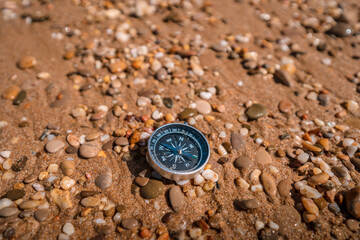 Fototapeta na wymiar Background image of compass lying in the sand on the beach with sea view, travel concept