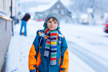 Happy kid boy having fun with snow on way to school