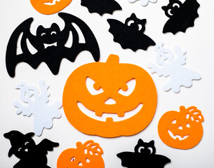 Frame of halloween decoration on pastel white background. Flat lay orange pumpkins, spooky spiders, bat, insects. Top view with copy space. Holiday greeting card mockup.