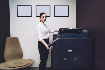 Businesswoman standing near office machine