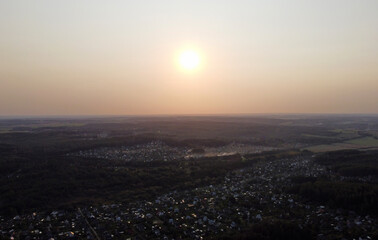 Beautiful top view at sunset on the forest and suburb with houses and a park